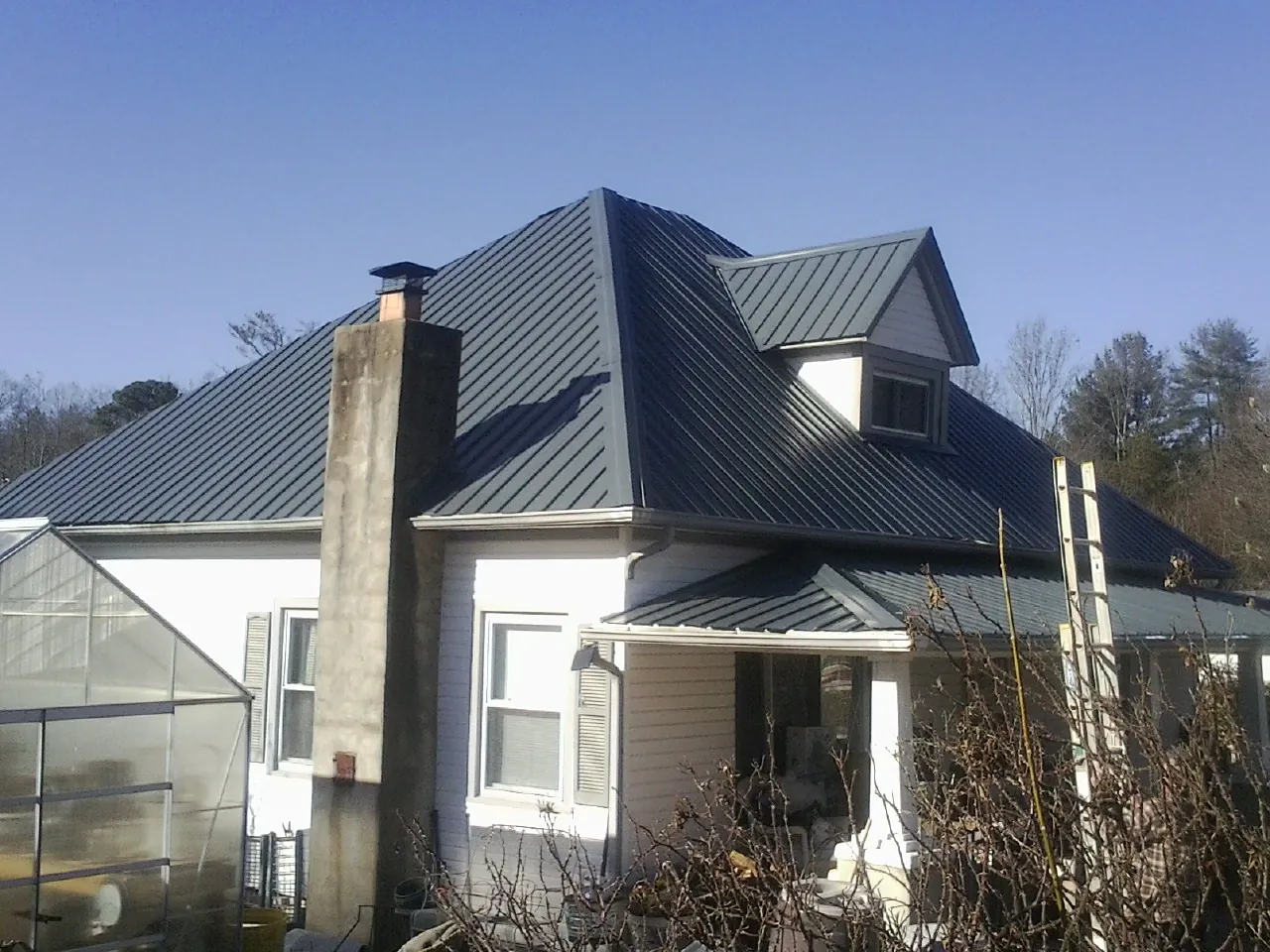 Dark blue standing seam metal roof on a white farmhouse with dormer — Slate & Tile Roof Repair by Roofing Brothers in Orrville