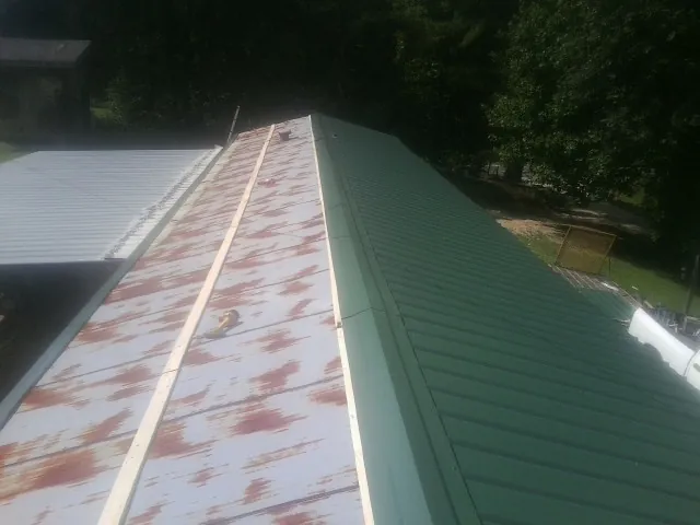 Old rusted panels beside newly installed green metal roofing — Wind Damage Roof Repair by Roofing Brothers in Orrville