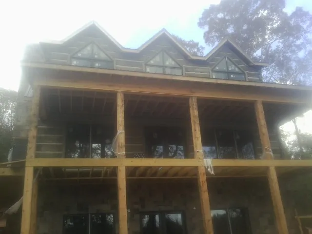 Dormers and porch framing on a large log home under construction — Roof Coating work by our crew in Orrville
