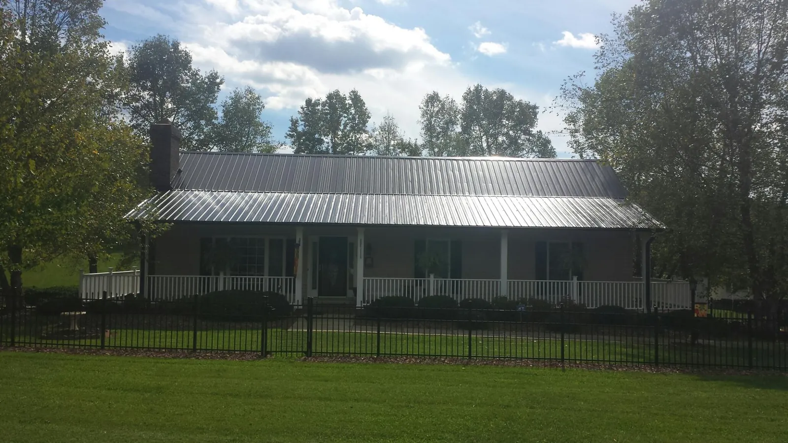 Gray metal roof on a brick ranch with a full width front porch — Gutter Guard Installation work by our crew in Orrville