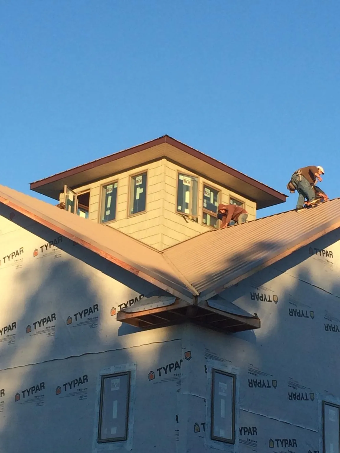 Roofers working around a rooftop cupola on a new metal roof at sunset — Roof Waterproofing in Orrville by Roofing Brothers